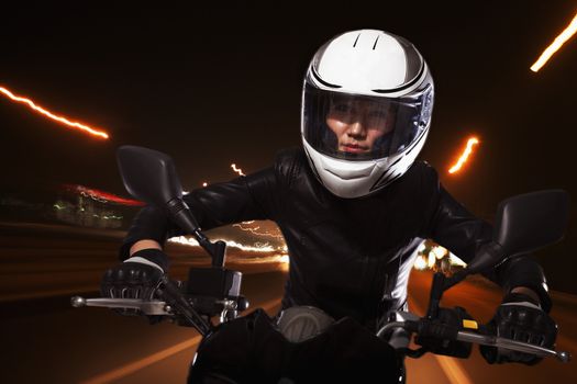 Young woman riding a motorcycle through the streets of Beijing, light trails 