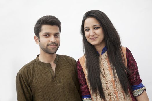 Portrait of smiling young couple wearing traditional clothing from Pakistan, studio shot