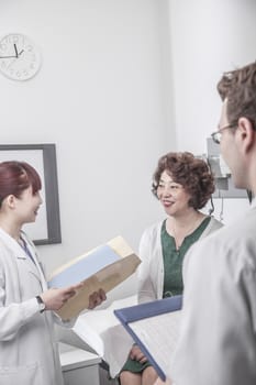 Two doctors holding medical charts discussing with a patient