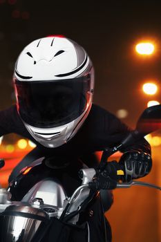 Young man riding a motorcycle at night through the streets of Beijing, front view