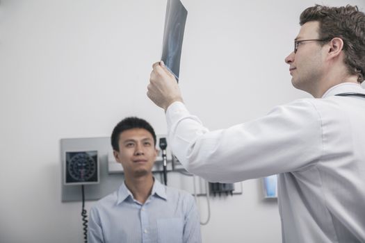 Doctor holding up and looking at x-ray of patient
