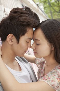 Happy young couple with arms around each other, foreheads touching and eyes closed