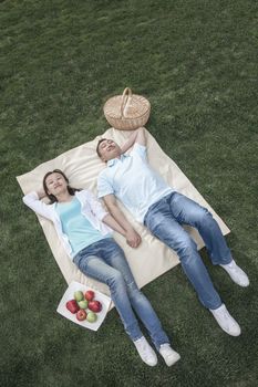 Couple lying on picnic blanket.