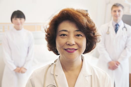 Portrait of three smiling doctors, female doctor at the front