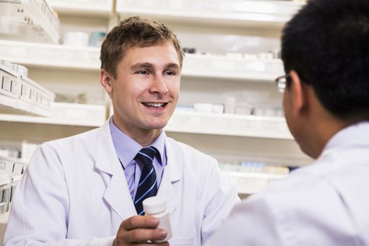 Smiling young pharmacist showing prescription medication to a customer