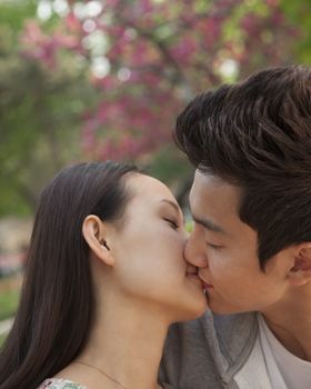 Young couple in love and kissing outdoors in the park