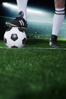 Close up of feet on top of soccer ball, night time in the stadium