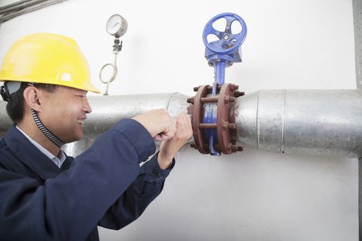 Smiling worker checking the oil pipeline equipment in a gas plant, Beijing, China