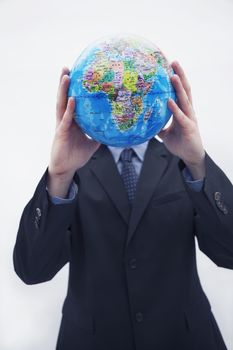 Businessman in a suit holding up a globe in front of his face, obscured face, studio shot