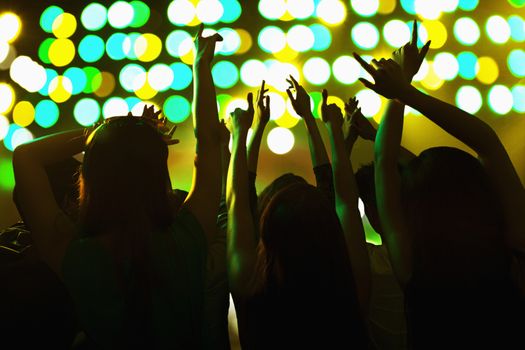 Audience watching a rock show, hands in the air, rear view, stage lights