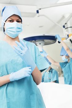Female surgeon putting on gloves in the operating room, getting prepared, looking at camera