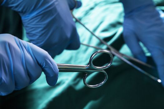 Close-up of gloved hands holding the surgical scissors and working, operating room, hospital