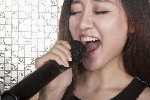 Close-up of young woman singing into a microphone at karaoke