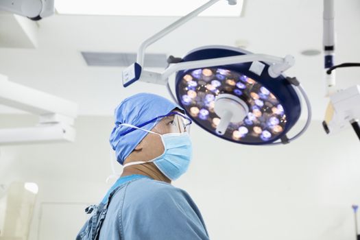 Side view of surgeon wearing a surgical mask and glasses in the operating room
