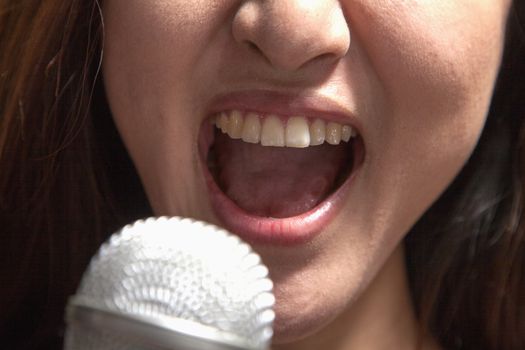 Close-up of young woman singing into a microphone at karaoke