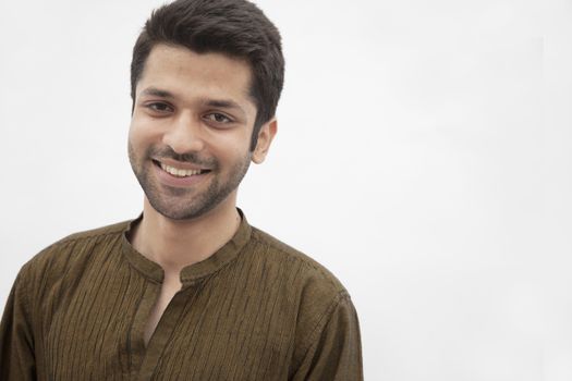 Portrait of smiling young man wearing traditional clothing from Pakistan, studio shot