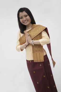 Portrait of smiling young woman with hands clasped together in traditional clothing from Laos, studio shot