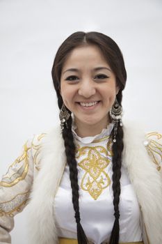 Portrait of young smiling woman with braids in traditional clothing from Kazakhstan, studio shot