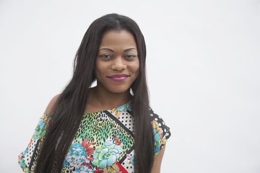 Portrait of young smiling woman with long hair in traditional clothing from Africa, studio shot