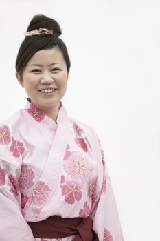 Portrait of young smiling woman in a pink Japanese kimono, studio shot