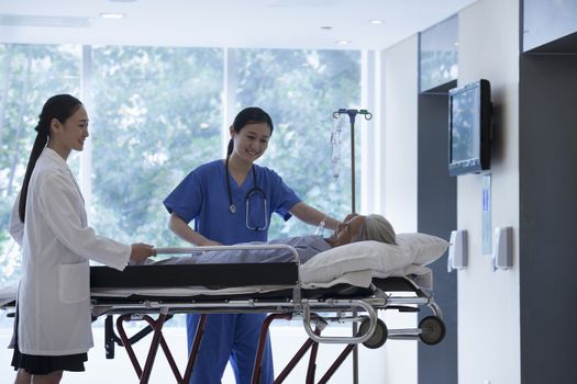 Female doctor and nurse wheeling a stretcher with a patient in the halls of the hospital