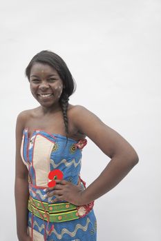 Portrait of young smiling woman with hand on her hip in traditional dress from Africa, studio shot