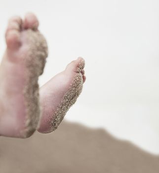 Close-up of children's feet in the sand