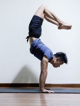 Upside down man doing yoga in a yoga studio, side view