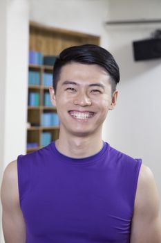 Portrait of young smiling man in a yoga studio, head and shoulders