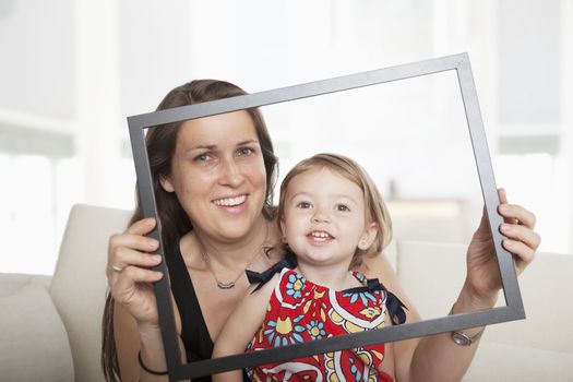 Mother and daughter holding up a picture frame and looking through it