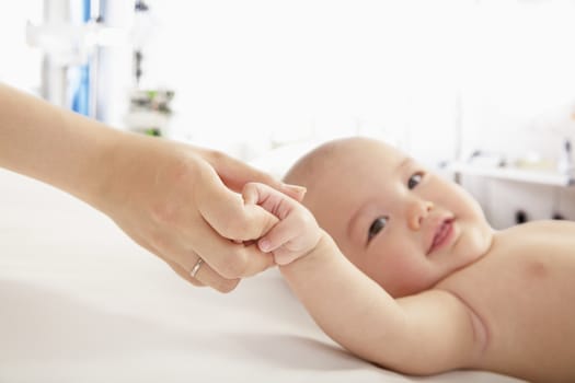 Mother holding her baby's hand in the doctors office