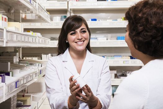 Smiling young pharmacist showing prescription medication to a customer