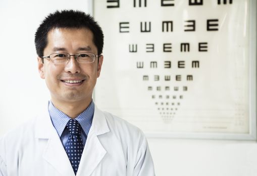 Portrait of smiling optometrist with an eye chart in the background
