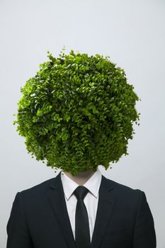Businessman with a circular bush obscuring his face, studio shot