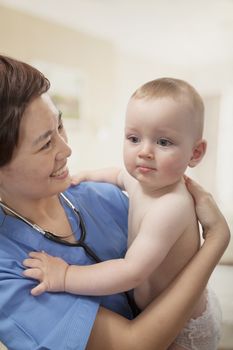 Smiling doctor holding baby in her arms in the doctors office