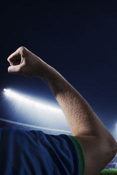 Soccer player flexing bicep in a stadium at night time