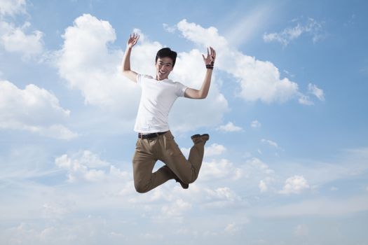 Young smiling man jumping in mid-air, sky and cloud background
