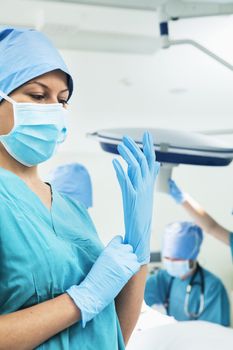 Female surgeon putting on gloves in the operating room, getting prepared