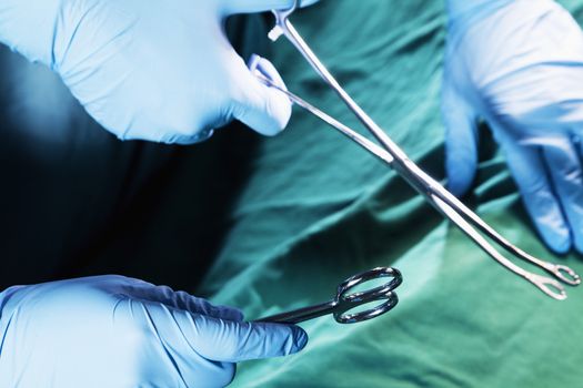 Close-up of gloved hands holding the surgical scissors and working, operating room, hospital