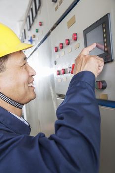 Smiling worker checking controls in a gas plant, Beijing, China