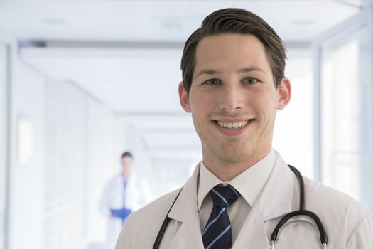 Portrait of young doctor in lab coat in the hospital, looking at camera, close-up