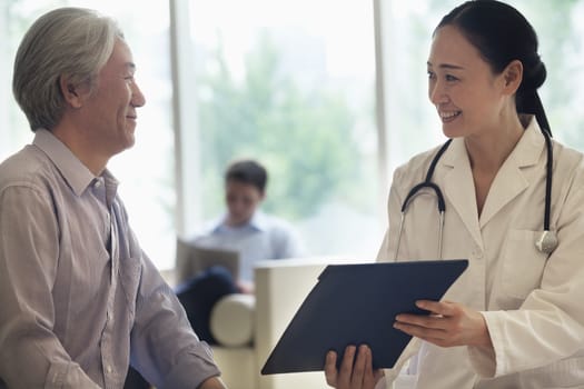 Female doctor and patient sitting down and discussing medical record in the hospital