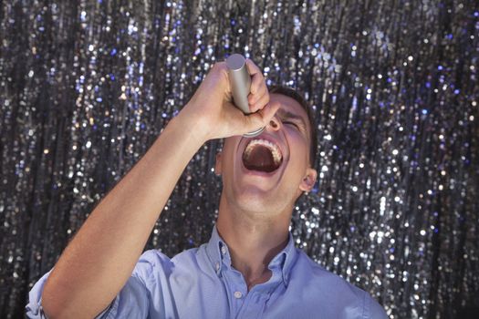Young man singing into a microphone at karaoke