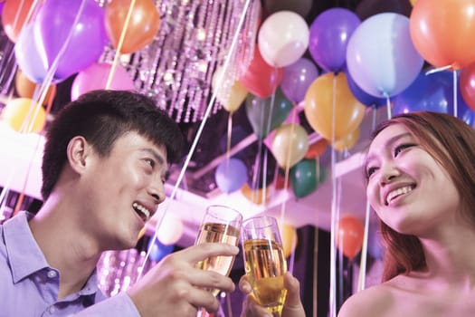 Two friends celebrating, toasting with champagne, nightclub in Beijing, balloons in the background