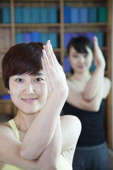Two young women stretching and doing yoga, close-up, looking at camera