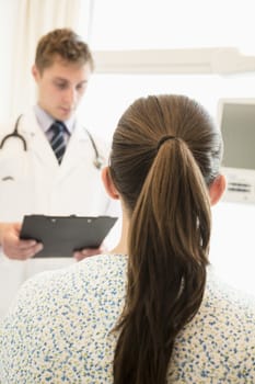 Doctor discussing medical chart with a patient sitting on a hospital bed 