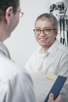 Doctor writing on medical chart with a smiling patient