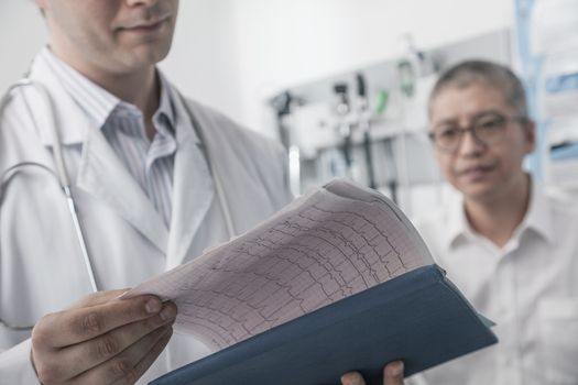 Doctor checking medical chart with patient in the background