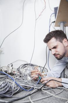 Frustrated man lying down trying to figure out and sort  computer cables