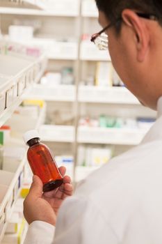 Pharmacist taking down and examining prescription medication in a pharmacy, rear view